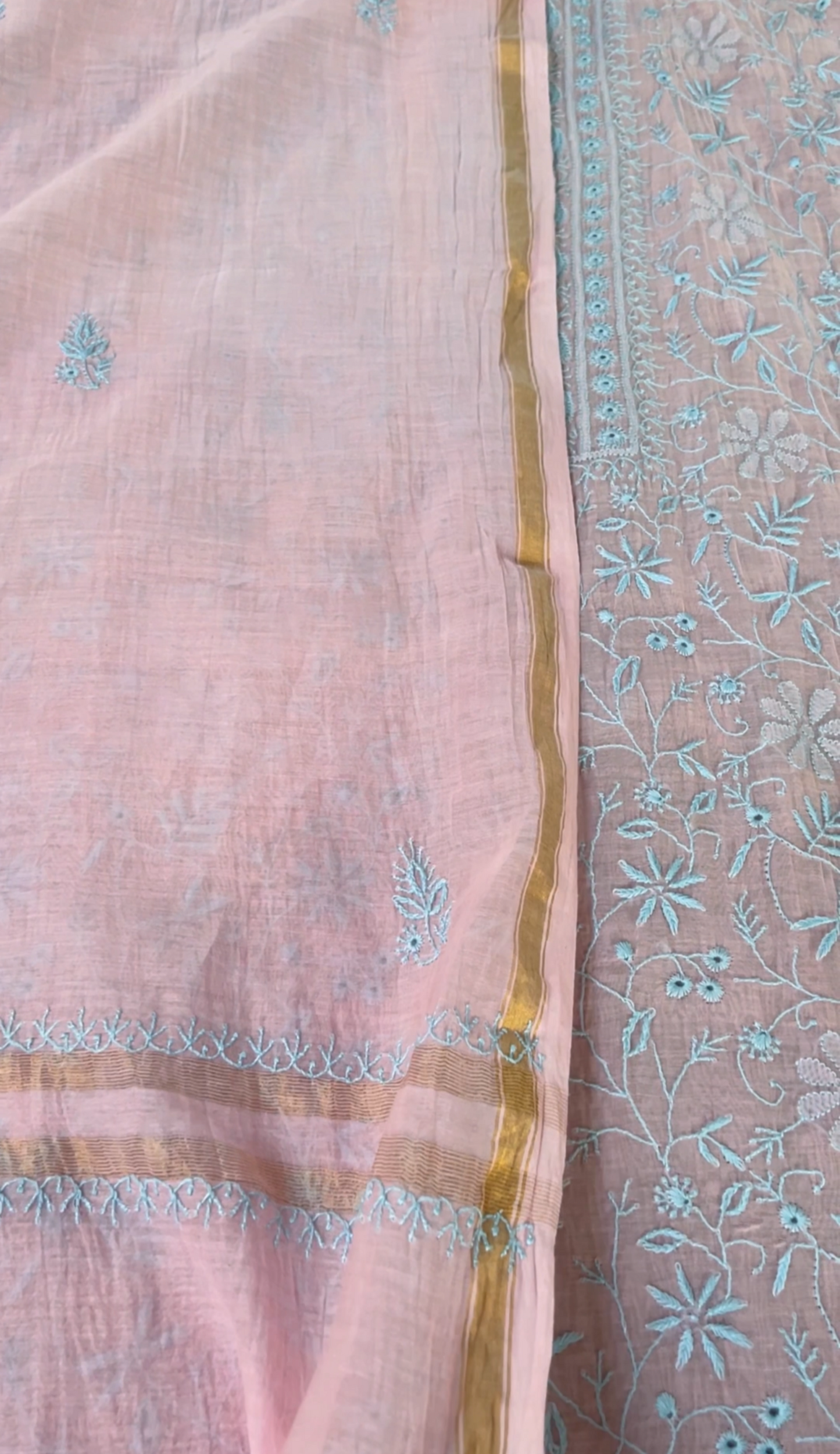 Blush pink mul chanderi fabric showcasing delicate blue chikankari embroidery with elegant gold trim.