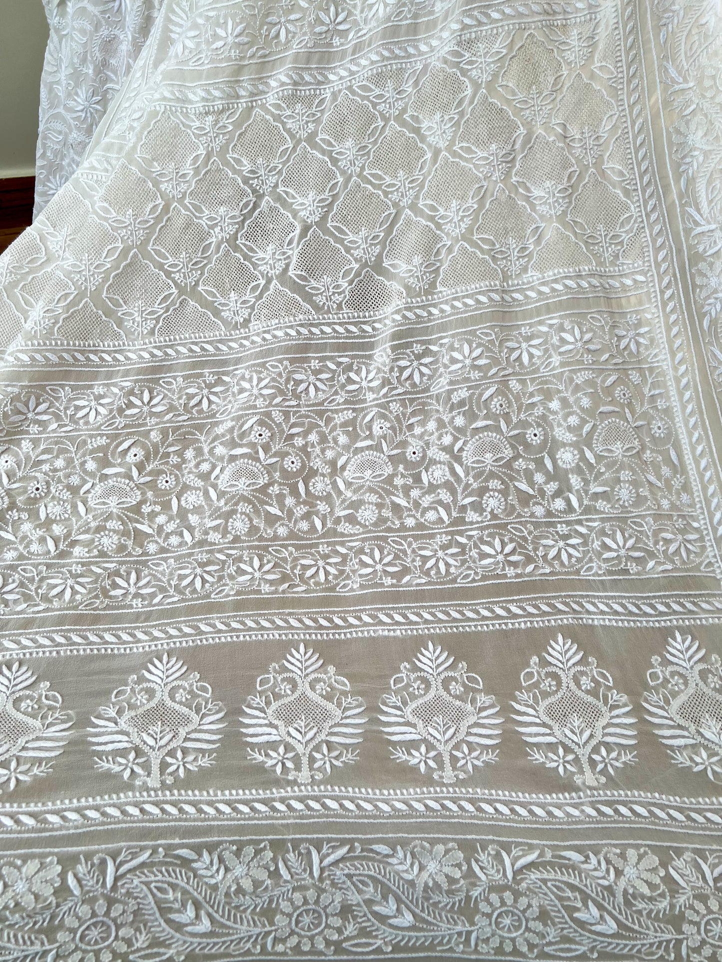 Intricate hand-embroidered Chikankari patterns on pearl white georgette fabric.