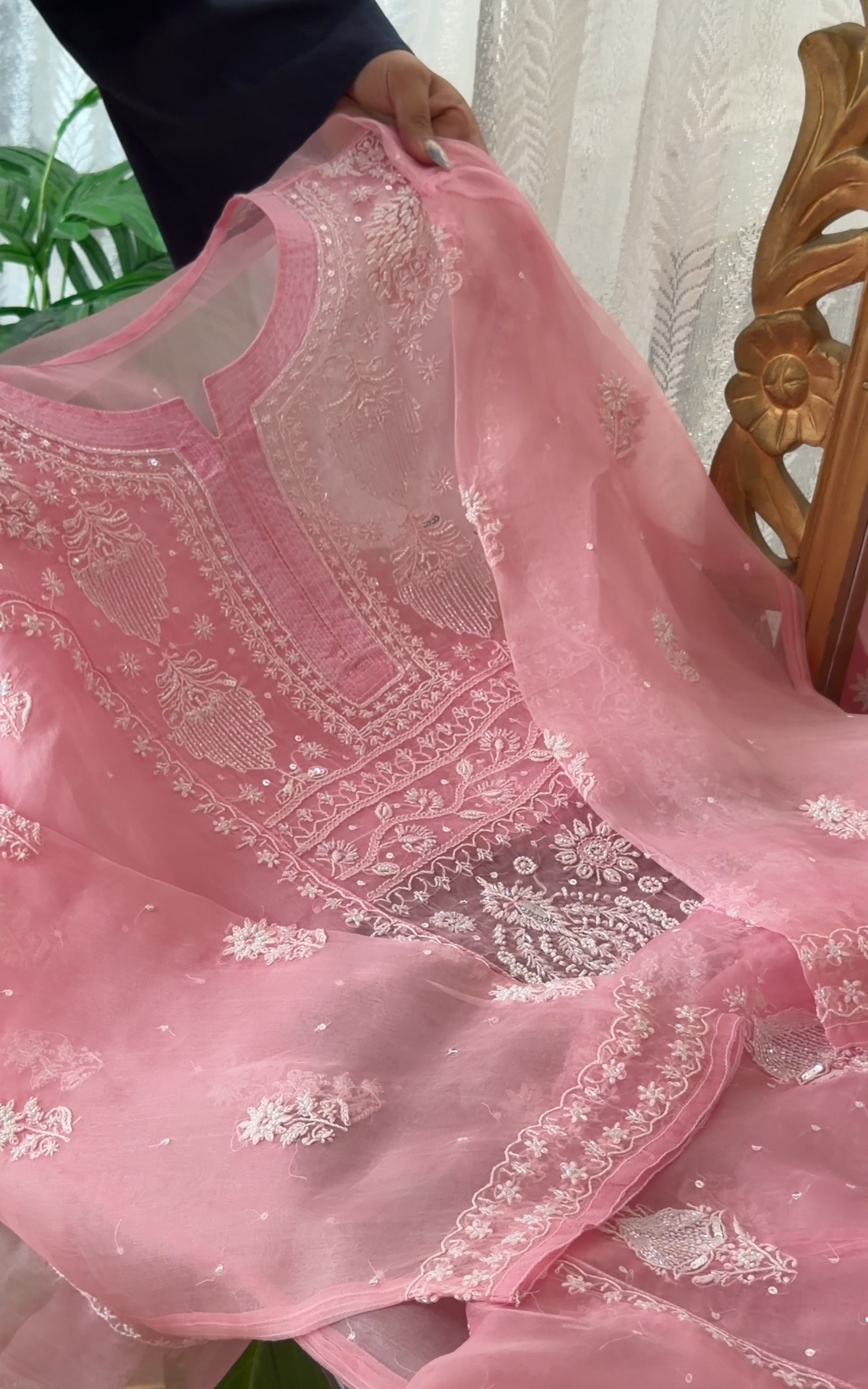 Pink Pure Organza Silk kurta set featuring intricate Chikankari and embellishments held in hands.